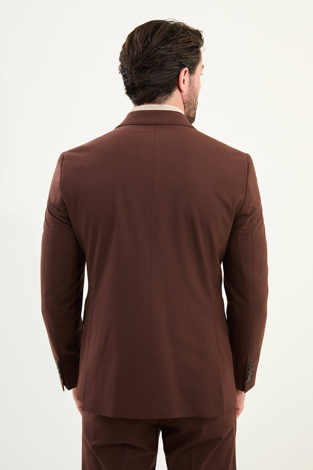 Men’s deep chocolate brown slim-fit double-breasted 6x2 suit with peak lapels, cotton-wool-viscose blend with stretch, designed for breathable comfort and wrinkle-resistant wear, styled with a cream turtleneck.