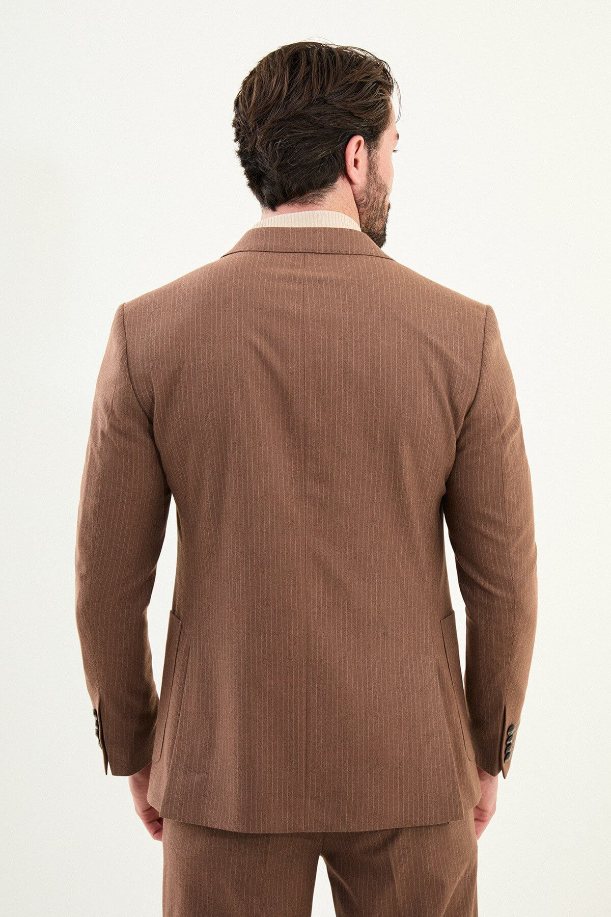 Men’s camel slim-fit mono-collar suit with pointed minimalist collar, matte micro-texture fabric, single-breasted jacket, and styled with a cream turtleneck for tonal winter dressing.