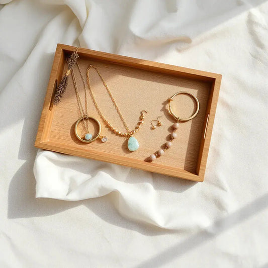 Delicate handmade necklaces, earrings, and a bracelet arranged on neutral fabric with soft natural light