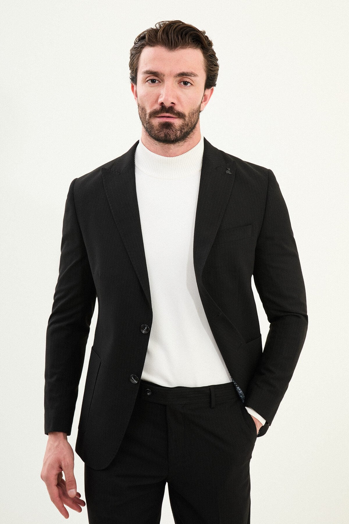 Men’s black mono-collar slim-fit suit with band/mandarin neckline, matte finish tailoring, single-breasted jacket styled with a white turtleneck, travel-ready stretch wool-viscose blend.