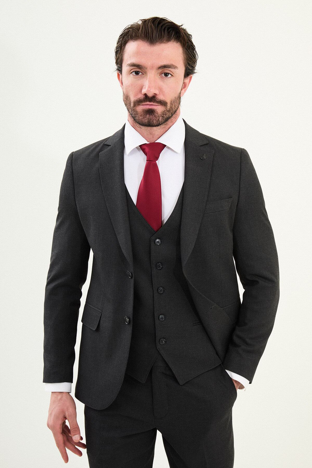 Men’s matte black slim-fit three-piece wool-blend suit with single-breasted jacket, V-neck waistcoat, slim tapered trousers, tonal buttons, and origami lapel pin.