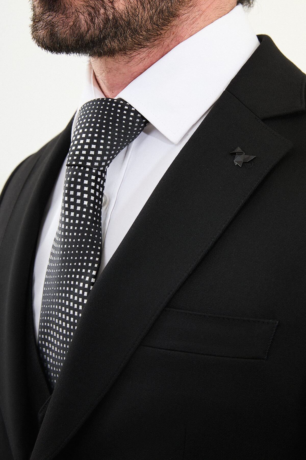 Men’s matte black slim-fit three-piece wool-blend winter suit with single-breasted jacket, notch lapels with AMF stitching, high-cut five-button waistcoat, tapered trousers, and black origami lapel pin.