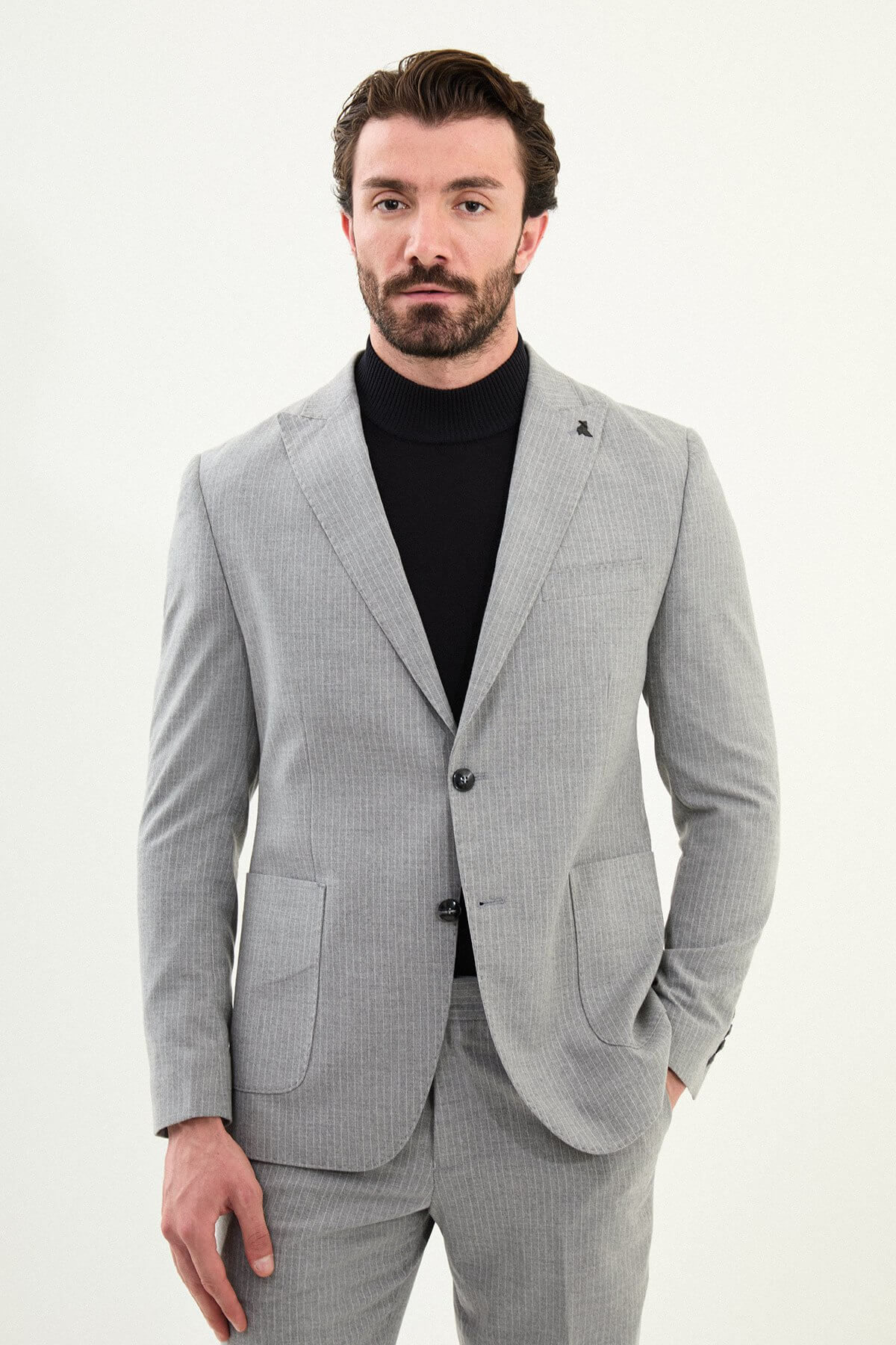 Men’s gray slim-fit mono-collar (mandarin collar) performance suit with 2-button single-breasted jacket, minimalist patch pockets, matte micro-texture fabric, styled with a black turtleneck.