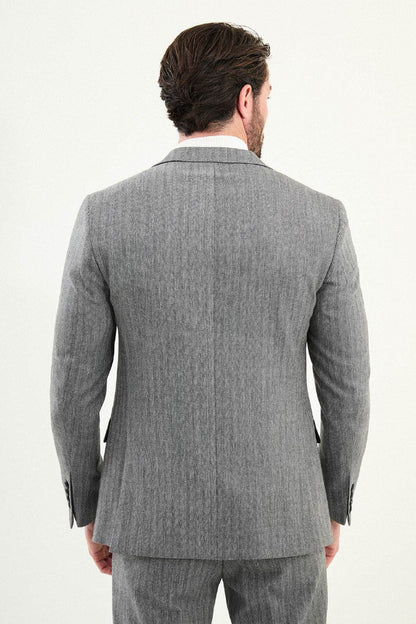 Men’s gray herringbone slim-fit single-breasted suit with structured shoulders and tailored waist, high-wool blend fabric with stretch, styled with a light gray fine-gauge turtleneck for winter.