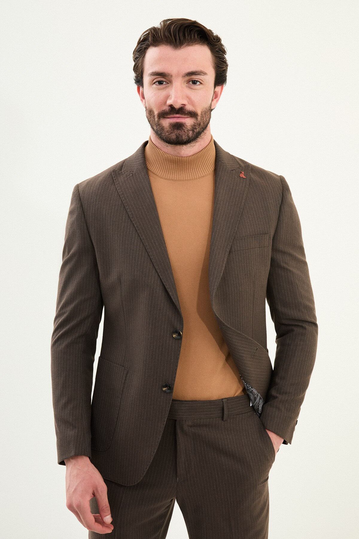 Men’s light brown slim-fit mono-collar (mandarin collar) winter suit with minimalist single-breasted jacket, matte micro-texture active-recovery fabric, styled with a camel turtleneck for tonal dressing.