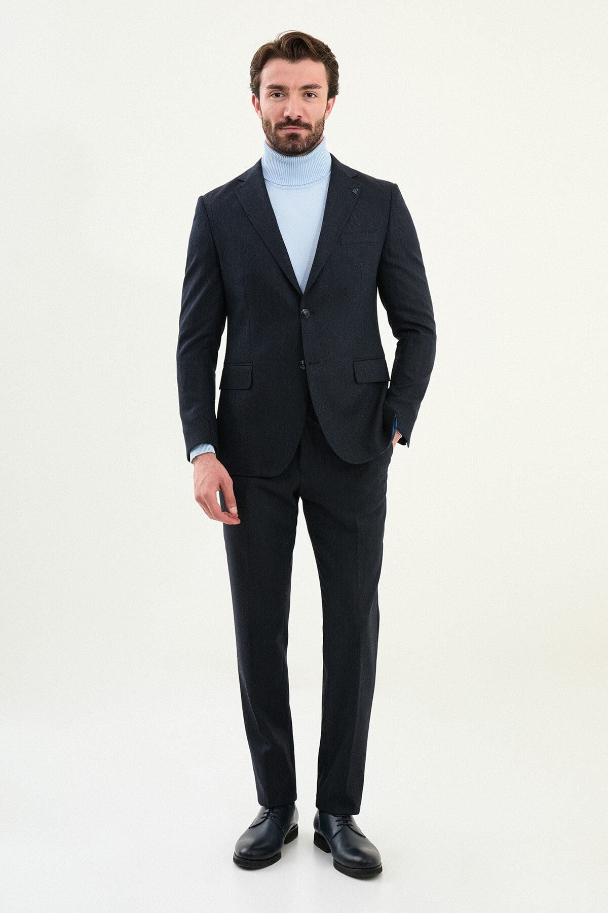 Men’s matte navy blue slim-fit single-breasted wool-blend suit with notch lapels and two-button closure, high-wool fabric with stretch for wrinkle-resistant winter wear, styled with a light blue turtleneck.