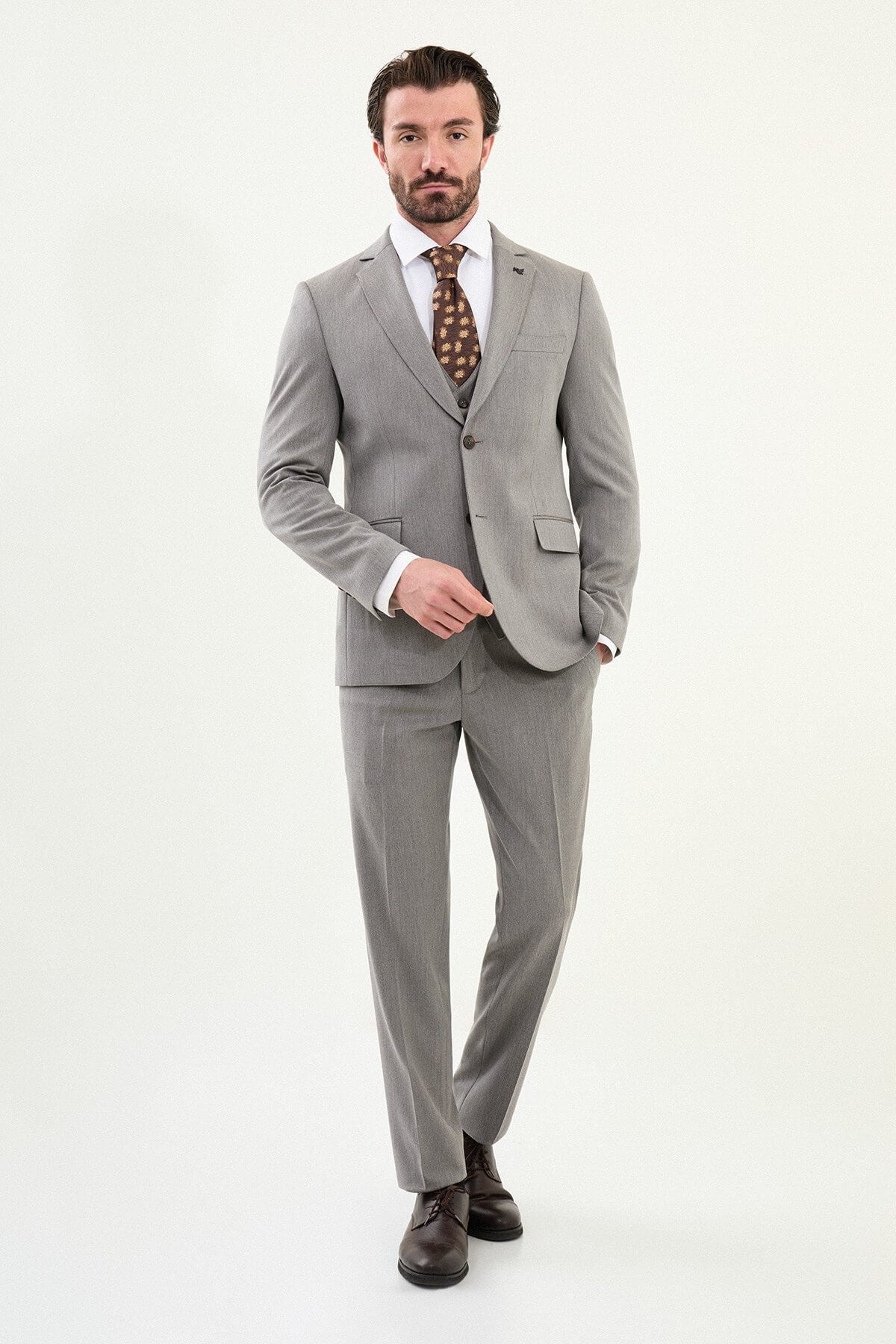 Men’s light gray slim-fit three-piece wool-blend winter suit with single-breasted jacket, notch lapels, matching waistcoat, dark buttons, and black origami lapel pin.